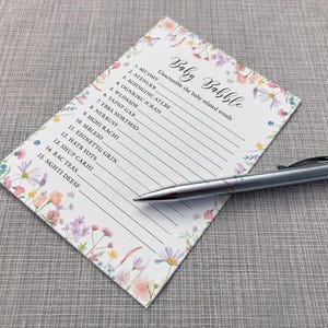 Baby Babble Baby shower game card featuring a pink, yellow, Lilac and peach wildflower design on a white background. Shown alongside a pen
