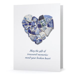 May include: A white greeting card featuring a heart made of blue and white ceramic shards. The heart is composed of various shapes and patterns. The card includes the text: "May the gift of treasured memories mend your broken heart."