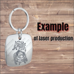 Pu&ograve; includere: Un portachiavi in ​​argento con un'etichetta quadrata che presenta un design inciso a laser in bianco e nero di una testa di lupo con un motivo a nodo. Il testo "MAKSIMOFF DESIGNS" &egrave; ripetuto attorno al bordo dell'etichetta. Il portachiavi &egrave; un esempio di produzione laser.