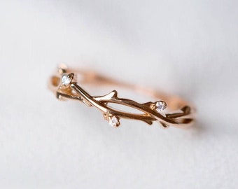 May include: A delicate gold ring with a twig design and small clear stones.