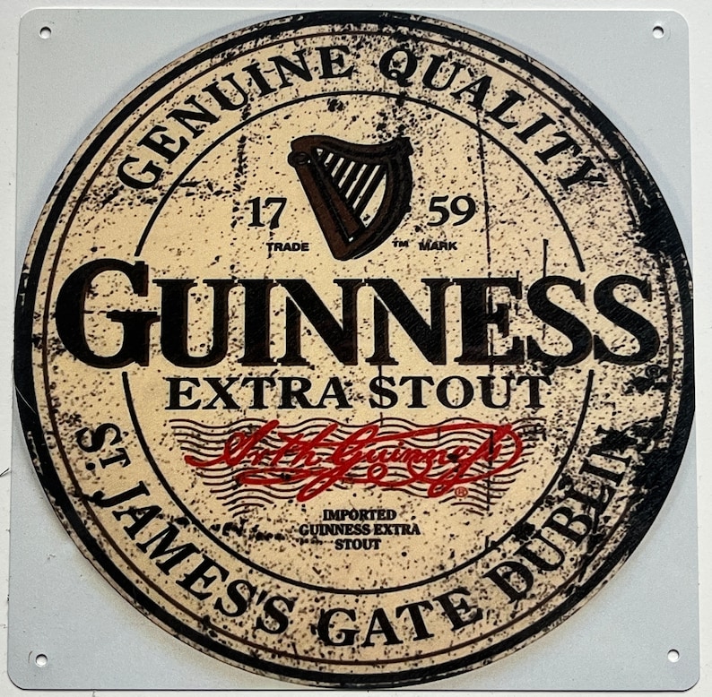 May include: A round, cream-colored metal sign with black lettering and a black harp logo. The sign reads "Genuine Quality", "17 Trade", "59 TM Mark", "Guinness Extra Stout", "St. James's Gate Dublin", and "Imported Guinness Extra Stout".