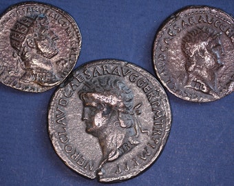 Op de afbeelding: Drie antieke Romeinse bronzen munten met Latijnse inscripties. De munten tonen portretten van Romeinse keizers en zijn in goede staat.