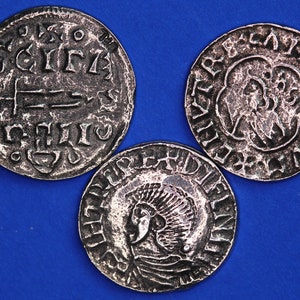 May include: Three silver coins with raised lettering and designs. The coins are on a blue background.