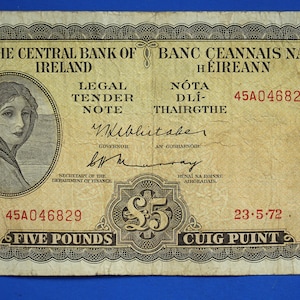 May include: A five pound Irish banknote with a portrait of a woman wearing a headscarf. The note is dated 23-5-72 and has the serial number 45A046829. The text "The Central Bank of Ireland" and "Banc Ceannais na hÉireann" is printed on the note.