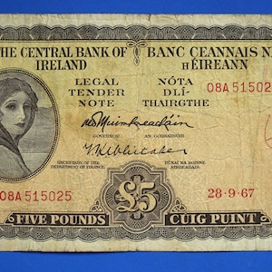 May include: A five pound Irish banknote with a portrait of a woman wearing a headscarf. The note is dated 28-9-67 and has the serial number 08A 515025. The text "The Central Bank of Ireland" and "Banc Ceannais na hÉireann" is printed on the note.