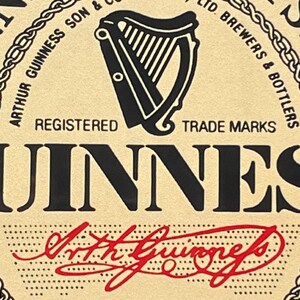 May include: A vintage-style Guinness Stout beer label with a black and white harp logo, the text "Guinness Stout", and the signature "Arthur Guinness" in red.
