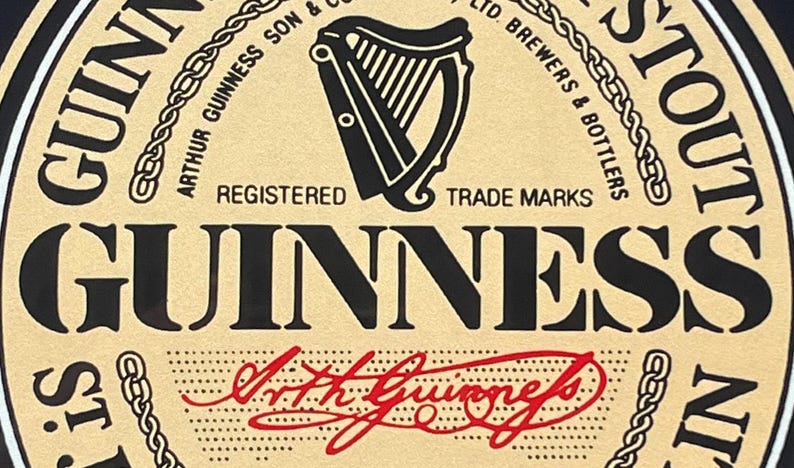 May include: A vintage-style Guinness Stout beer label with a black and white harp logo, the text "Guinness Stout", and the signature "Arthur Guinness" in red.