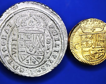 Op de afbeelding: Twee antieke zilveren en gouden munten met een wapenschildontwerp. De zilveren munt heeft een verhoogde rand en de gouden munt heeft een parelrand.