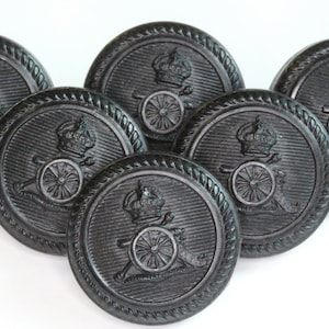 Peut inclure: Six boutons en plastique noir avec un motif en relief d'une couronne et d'une roue de canon.