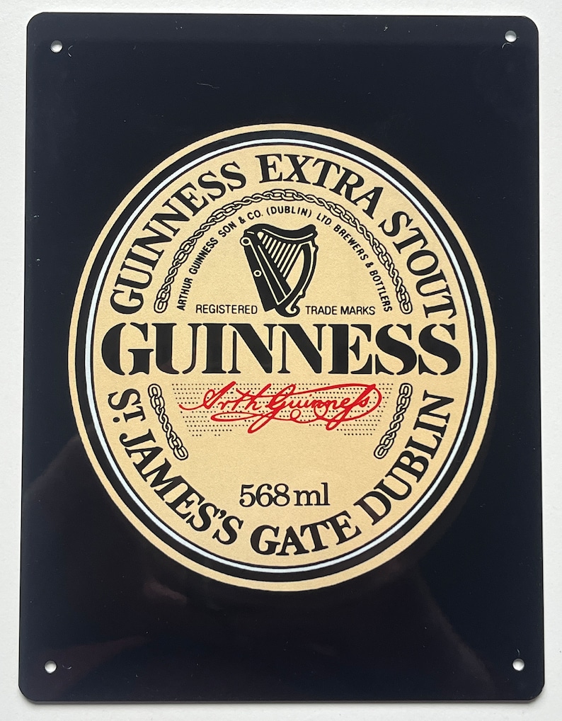 May include: A black and gold metal sign with the Guinness Extra Stout logo. The logo features a harp, the words "Guinness Extra Stout", "Arthur Guinness Son & Co. (Dublin) Ltd. Brewers & Bottlers", "Registered Trade Marks", "Guinness", "St. James's Gate Dublin", and "568 ml".