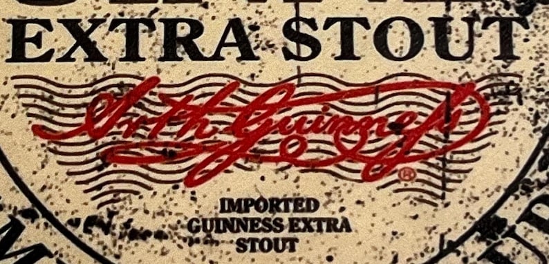 May include: A close-up of a vintage-style label for Guinness Extra Stout beer. The label features a red stamp with the text "Arthur Guinness Son & Co.", along with the words "Imported Guinness Extra Stout".