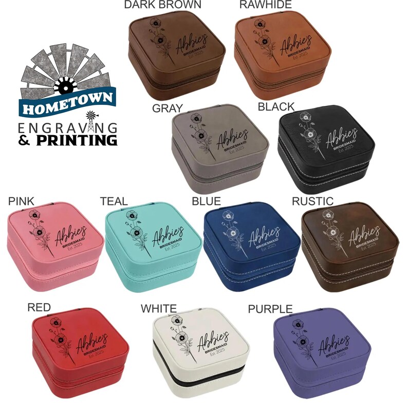 A collection of personalized travel jewelry cases is displayed in various colors, including dark brown, rawhide, gray, black, pink, teal, blue, rustic, red, white, and purple. Each case features an engraved floral design with a customizable name or text, making them ideal for bridesmaid gifts or personalized keepsakes. The Hometown Engraving & Printing logo is visible, indicating customization services.
