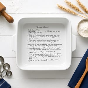 ustom engraved recipe casserole dish shown in a rustic kitchen setup with rolling pin, flour bowl, wheat stalks, and navy linens. White ceramic baking dish designed for handwritten recipes, perfect as a wedding gift, heirloom kitchen keepsake, or personalized baking dish.