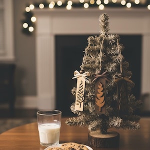 Rustic neutral Christmas ornaments with handmade wooden tree designs and raffia bows.