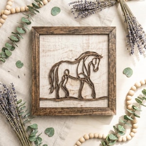 May include: A wooden framed art piece featuring a horse silhouette. The horse is crafted from thin, brown wood strips, set against a light-colored wooden background. The frame is a darker brown with a wood grain pattern. The artwork is surrounded by decorative elements.