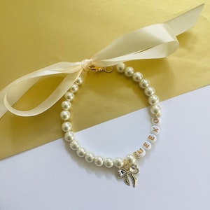 May include: A white ceramic mug with a black handle and the text "But First, Coffee" in a bold, black font. The mug is set against a blurred background, suggesting a cozy setting.