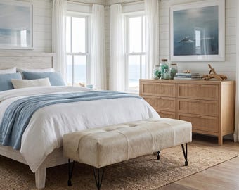 May include: A bedroom featuring a white wooden bed frame with blue and white bedding, a light-colored tufted bench with black metal legs, and a six-drawer wooden dresser with woven rattan panels, all set on a textured natural fiber area rug.