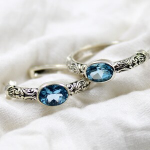 May include: Two silver rings with ornate designs and blue topaz gemstones.
