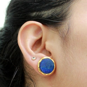 Peut inclure: Une paire de boucles d'oreilles en or avec une pierre ronde en lapis-lazuli bleu sertie dans chaque boucle d'oreille.
