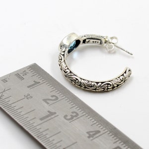 May include: Sterling silver hoop earrings with a blue gemstone and intricate floral detailing. The earrings are approximately 1 1/2 inches in diameter.