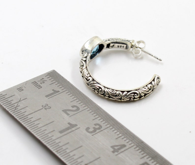 May include: Sterling silver hoop earrings with a blue gemstone and intricate floral detailing. The earrings are approximately 1 1/2 inches in diameter.