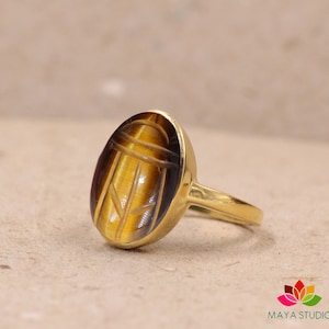 May include: Gold ring with a carved tiger's eye stone in the shape of a scarab beetle.