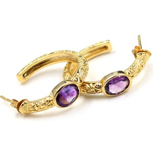 May include: Gold hoop earrings with ornate detailing and purple amethyst gemstones.