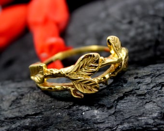May include: A gold ring with a delicate design of leaves and branches. The ring is made of a smooth, shiny metal and has a simple, elegant style.