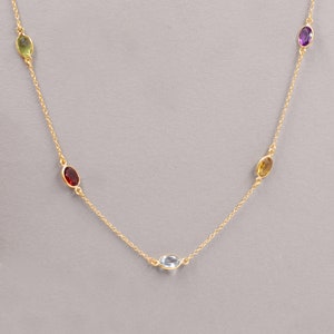 May include: A gold chain necklace with five oval-shaped gemstones. The stones are green, red, blue, yellow, and purple.