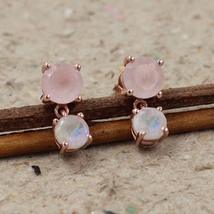 Könnte beinhalten: Ohrringe aus Roségold mit einem Design aus rosa und weißen Edelsteinen. Der obere Edelstein ist rosa und der untere Edelstein ist weiß mit einem regenbogenfarbenen, irisierenden Schimmer.