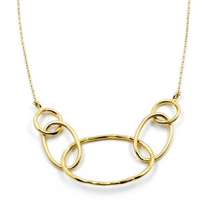 May include: A gold-colored necklace featuring a series of interconnected oval and circular links. The necklace has a delicate chain and a modern, minimalist design. The links have a hammered texture, adding visual interest.