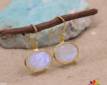 May include: A pair of gold dangle earrings with oval-shaped moonstone gemstones. The earrings have a simple design and are perfect for everyday wear.