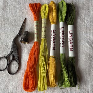 May include: Four spools of embroidery floss in orange, yellow, green, and a darker green. The spools are labeled "Lingarn" and "Made in Sweden".