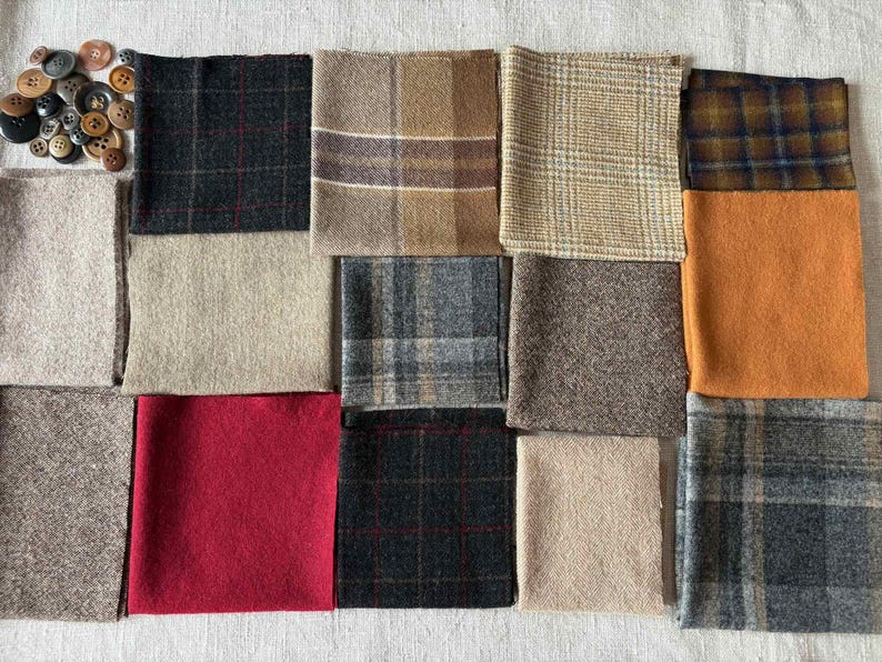 May include: A collection of fabric swatches in various colors and patterns, including plaid, solid, and textured designs. The color palette includes shades of brown, gray, red, and orange. A pile of assorted buttons is in the upper left corner.