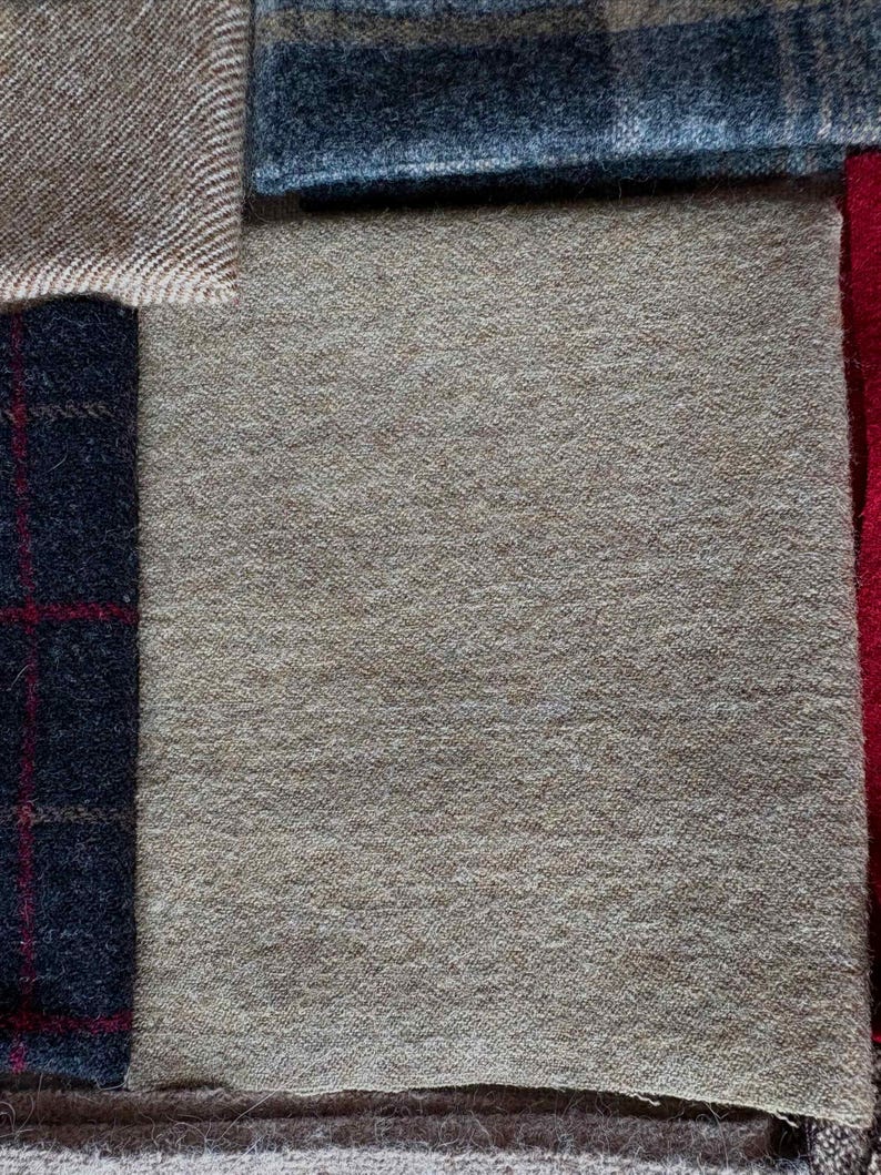 May include: A collection of fabric swatches in various textures and colors. The swatches include a light brown herringbone weave, a dark blue plaid, a solid tan, and a dark blue plaid with red accents. The fabrics appear to be wool or a wool blend.