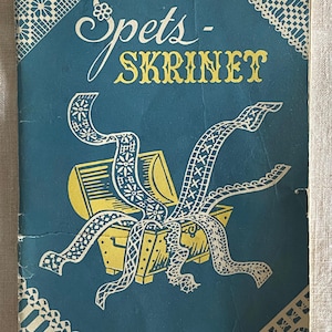 May include: A blue book cover with the title "Spets-Skrinet" in yellow lettering. The cover features a yellow chest with white lace spilling out of it.