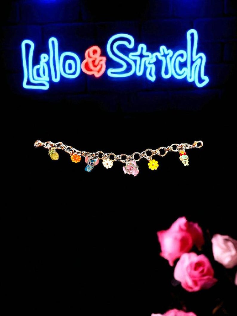 May include: A gold-colored charm bracelet featuring colorful enamel charms of cartoon characters and a pineapple. The bracelet is displayed against a black background with a neon sign that reads "Lilo & Stitch".