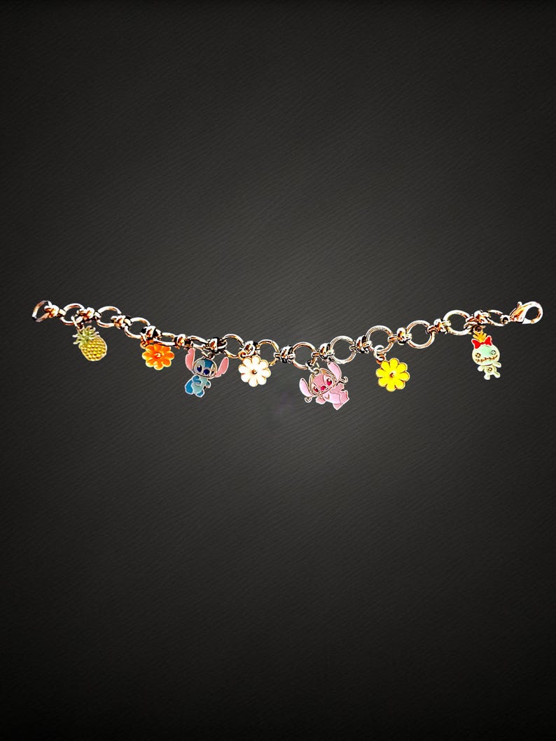 May include: A charm bracelet featuring colorful enamel charms. The charms include a pineapple, flowers, and cartoon characters. The bracelet is made of linked metal and has a lobster clasp closure. The charms are in various colors.