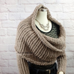 May include: A brown knitted cowl neck sweater with long sleeves. The sweater is draped over a mannequin and has a loose, flowing fit.