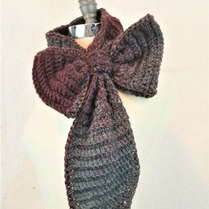 May include: A long, crocheted scarf in shades of burgundy and gray, tied in a bow around a mannequin's neck.
