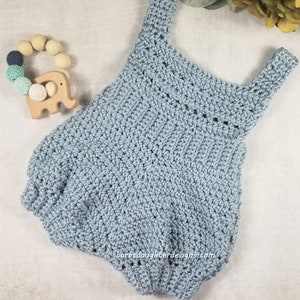May include: A light blue crocheted baby romper with a wide, scoop neckline and thin straps. The romper has a gathered, bubble-like bottom.