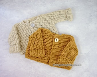 May include: Two knitted baby cardigans, one beige and one mustard yellow, with wooden buttons. The cardigans are laid out on a light gray surface.