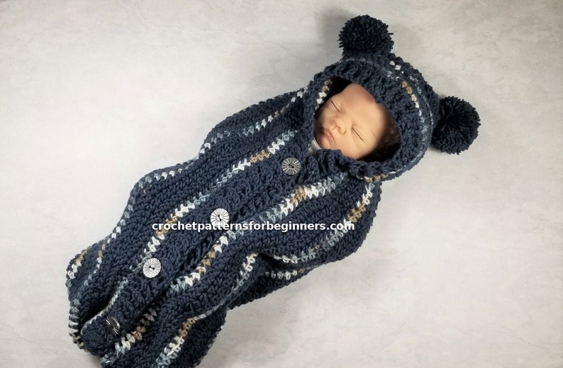 May include: A blue and white striped crocheted baby sleeping bag with a hood and pom-poms. The sleeping bag has buttons down the front and is made with a soft yarn. crochetpatternsforbeginners.com
