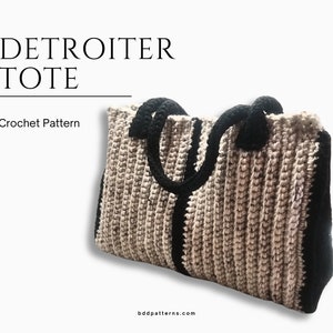 May include: Crochet pattern for a beige and black tote bag. The bag has a wide, flat base and two black handles. The text "DETROITER TOTE" is at the top of the image.