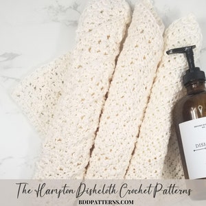May include: Three white crocheted dishcloths folded on a white marble surface. A brown glass bottle with a white label that reads "Dish Soap" is next to the dishcloths. The text "The Hampton Dishcloth Crochet Patterns BDDPATTERNS.COM" is at the bottom of the image.