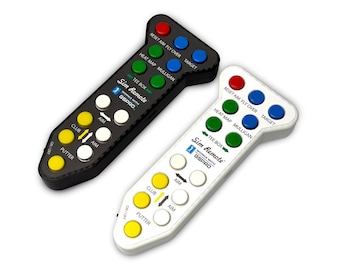 Puede incluir: Dos mandos a distancia para simulador de golf, uno negro y otro blanco, con múltiples botones de colores. Los mandos a distancia tienen el texto "Sim Remote" y "WORKS WITH GSPRO". Los botones están etiquetados con funciones como "Putter" y "Target".