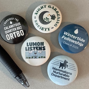 May include: A collection of six round buttons with various designs and text. One button reads "I survived the calamitous quarter 882 ORTBO." Other buttons include "Night Gardening Society," "Lumon Listens," "Wintertide Fellowship Class of 2025," and "Mammalians Nurturable Department."