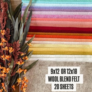 May include: A set of 20 sheets of 9x12 or 12x18 wool blend felt in a variety of colors. The felt is arranged in a rainbow pattern, with the colors ranging from dark brown to light pink. The felt is displayed on a wooden surface.