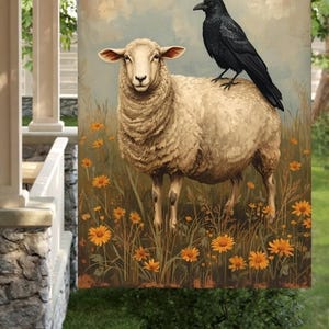 May include: A decorative garden flag featuring a sheep with a black crow perched on its back. The artwork is set in a field of tall grass and orange flowers, with a soft, vintage-style background.