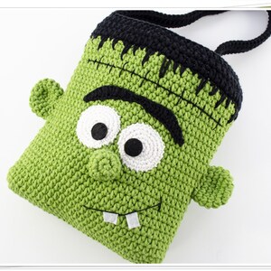 Puede incluir: Bolso de crochet verde en forma de monstruo de Frankenstein con pelo negro, ojos blancos y una cicatriz cosida. El bolso tiene un asa de crochet negro.